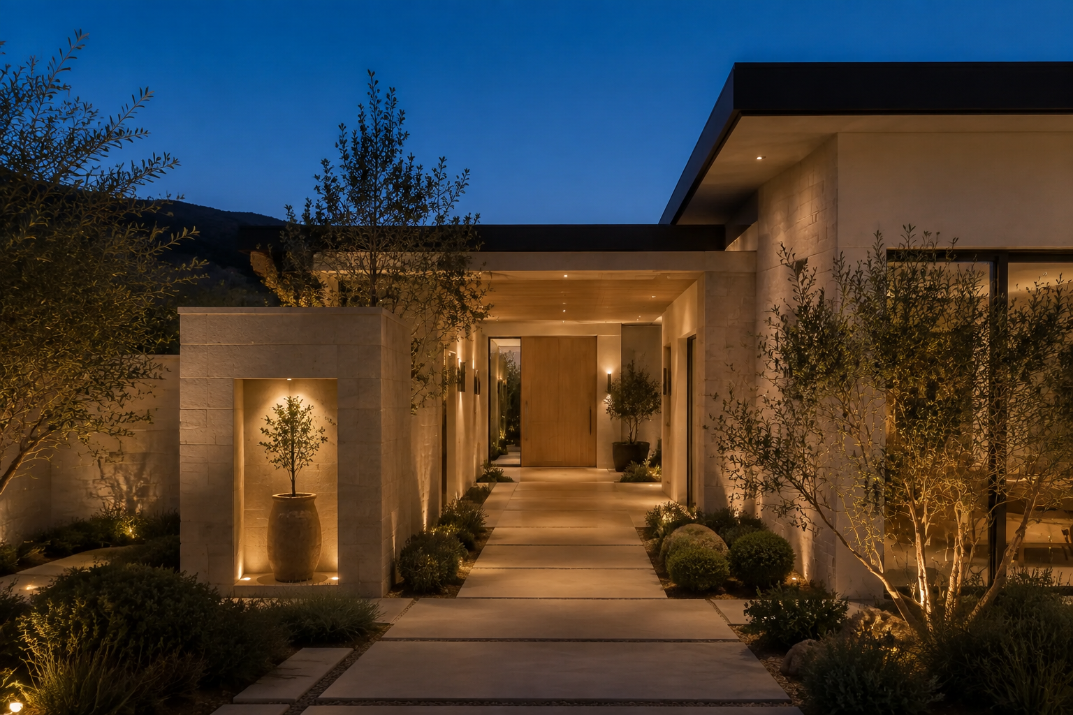 The illuminated arrival courtyard of a contemporary mountain home at blue hour